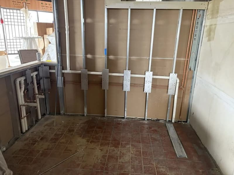 Room with exposed wall framing and pipes during renovation
